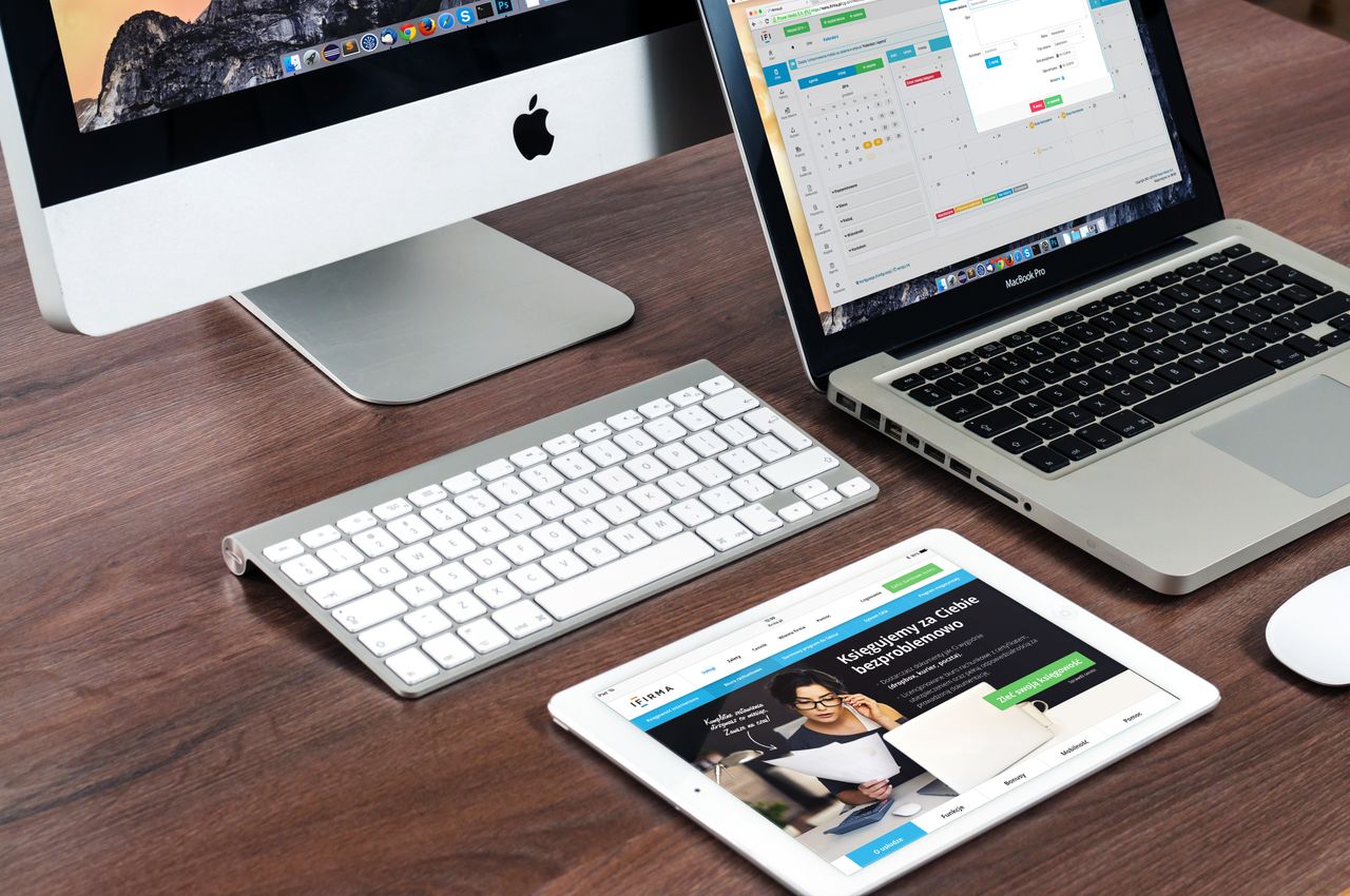 services-01 A sleek office desk setup featuring Apple devices: iMac, MacBook, and iPad.
